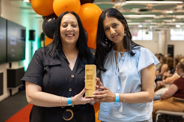 Two women holding a trophy together.