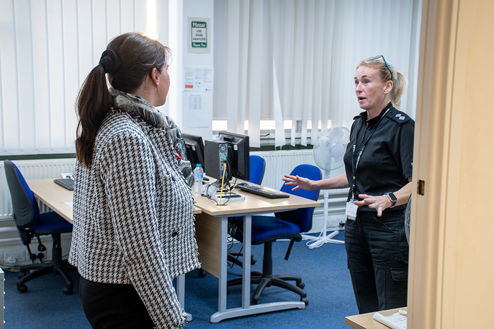 Two women in an office mid discussion. One person is wearing a uniform,