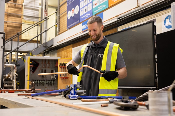 A man holding a piece of metal inside a workshop.