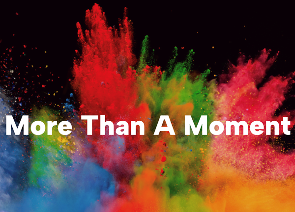 The key-graphic for More Than A Moment. The background graphic features an explosion of multicoloured powder frozen in shot with the words 'More Than A Moment' overlayed on-top.