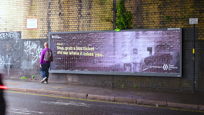 The full black billboard on a tunnel wall with the slogan 'Stop grab a bus ticket and see where it takes you'