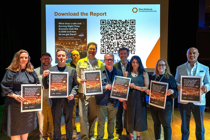 Group of ten people holding up a report with a screen behind them