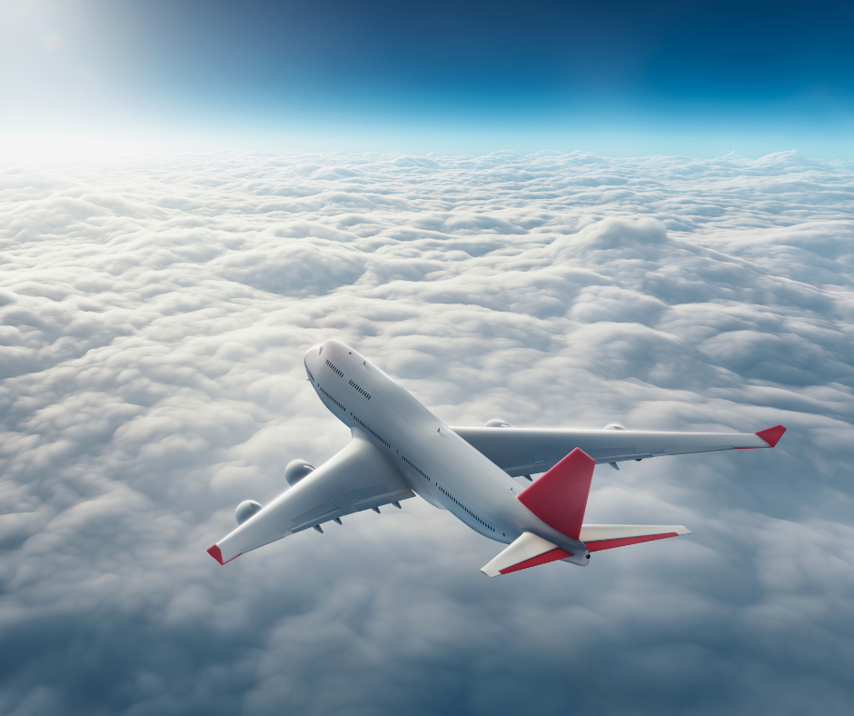 A white airplane with red wing tips flying above the clouds.
