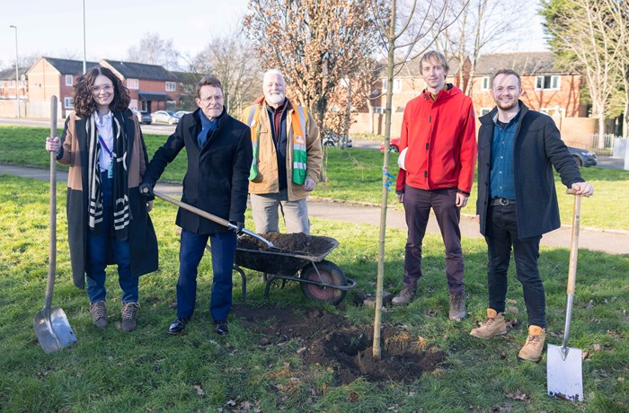 Francesca Marsden, senior regional manager at Amazon, Andy Street, Mayor of the West Midlands, Ian McDermott, of Birmingham Tree People, Jeff Grant, West Midlands Combined Authority's Forest Partnership coordinator, and Harry Munt, urban forest technician at Treeconomics, at Loxton REC Play Park in Birmingham, with spades and trees in hand during a tree planting session. There is a wheel barrow placed between them and houses in the background.