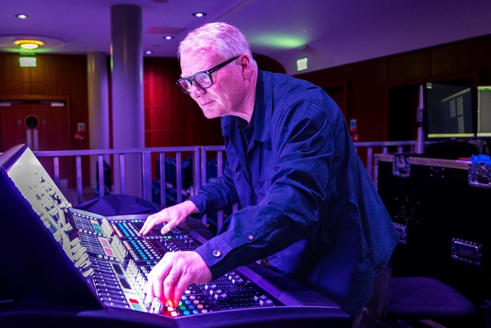 Mayor Parker standing over a large control desk with dozens of buttons and switches