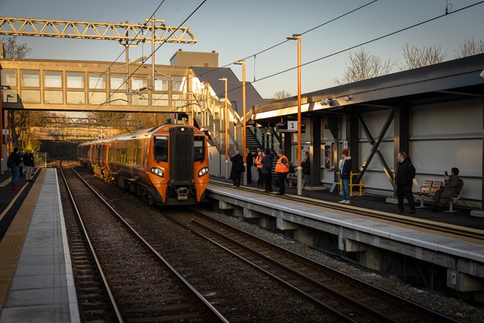 Train pulling into a platform where people are waiting