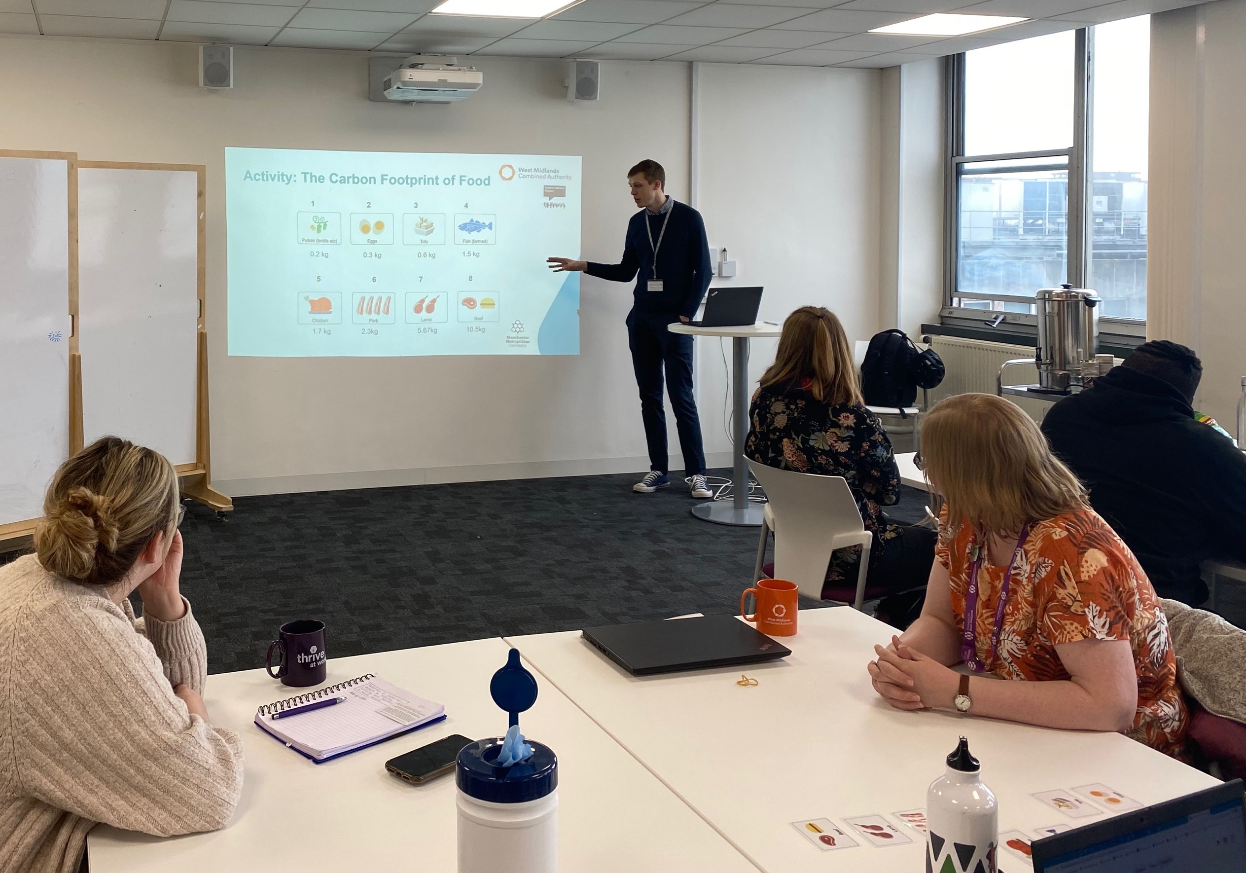 Colleagues in a classroom with a presenter presenting information on Carbon Footprint