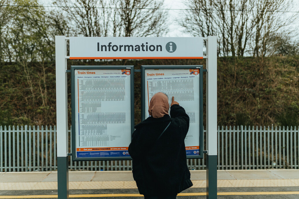 Woman looking at train timings on a platform
