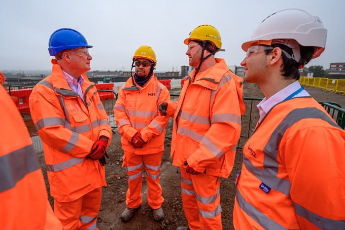 Three apprentices in orange hi-visibility construction kit talk to mayor Richard Parker at the Curzon Street site