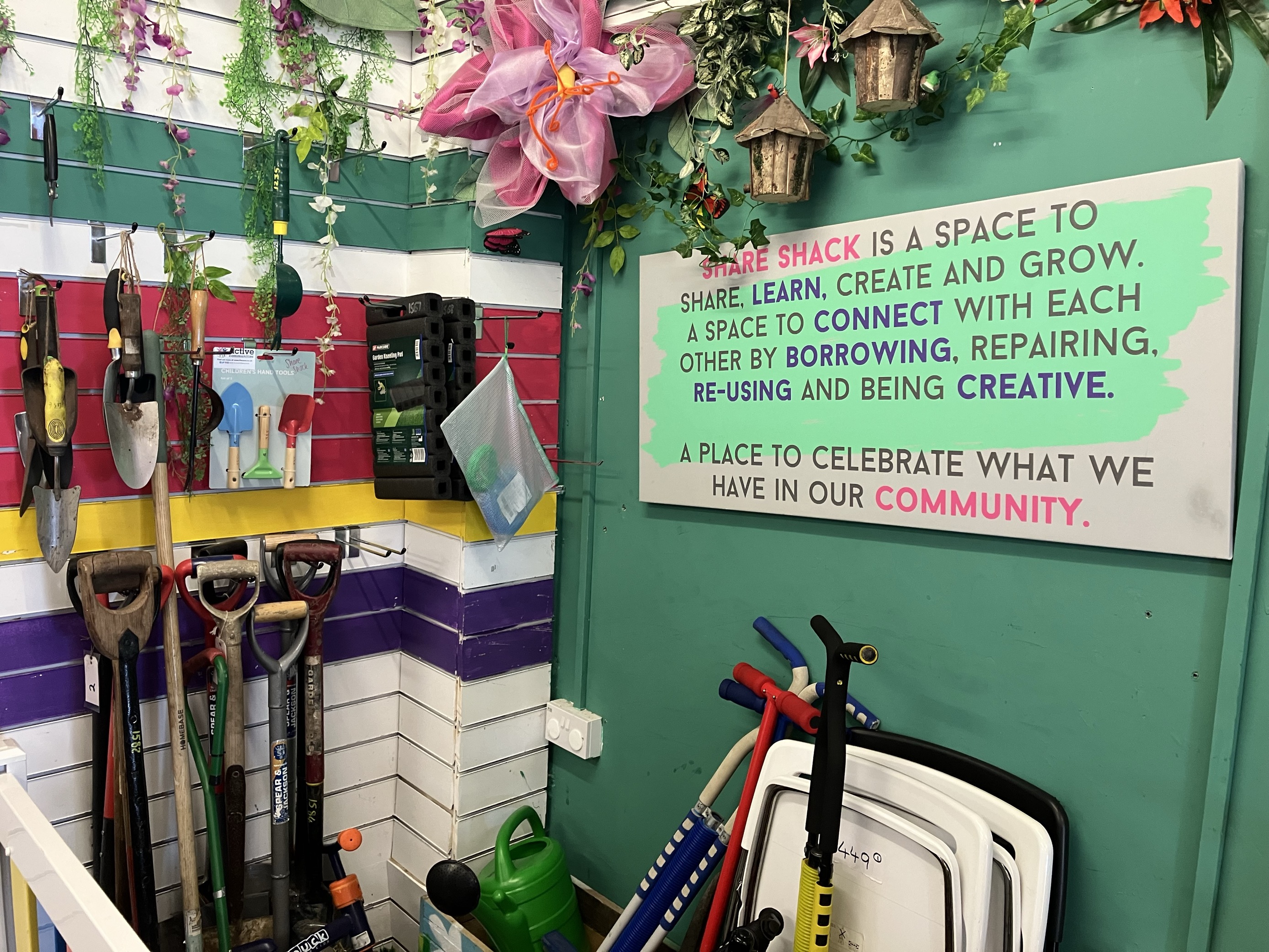 A colourful wall with gardening tools hung up