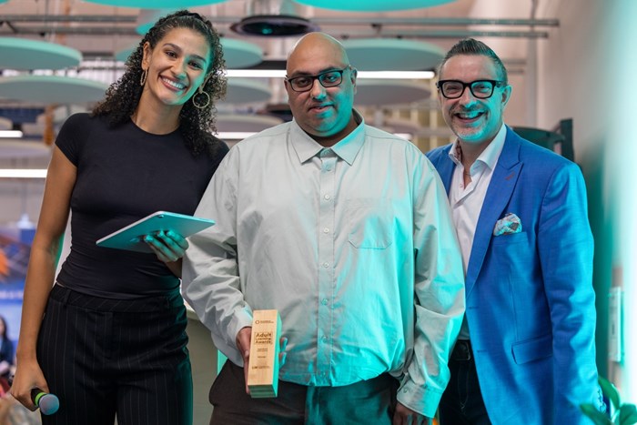 A man holding an award with a man and a woman either side of him.